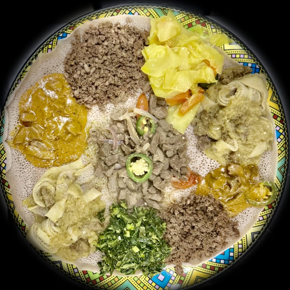 A large platter of Ethiopian food with various stews, meats, and vegetables served on injera bread.