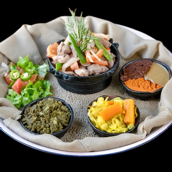 Ethiopian injera bread with various stews, vegetables, and spices in small black bowls.